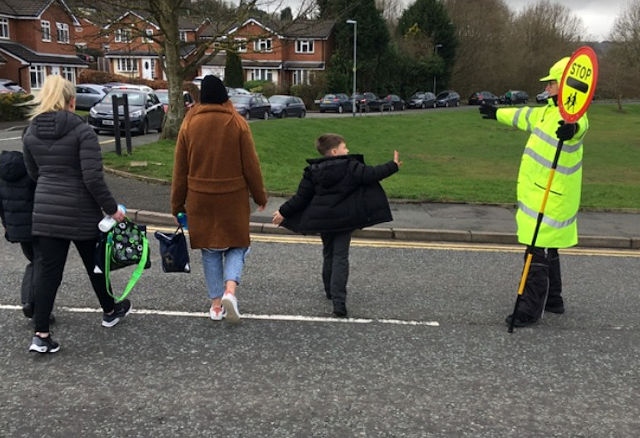 A lollipop man gets a wave from a St Vincent's Primary School pupil at the Caldershaw Road crossing in Norden