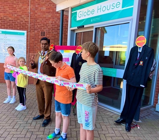 Mayor Ali Ahmed talks as children hold a ribbon in front of Globe House