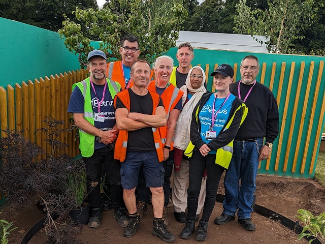 A group of Petrus volunteers and service users, halfway through the build