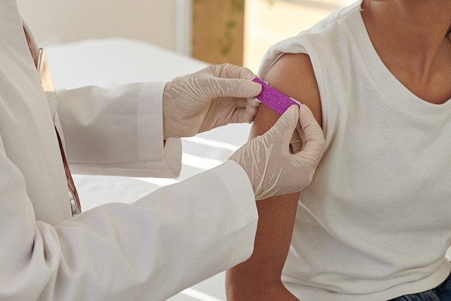 Doctor applying plaster on arm of patient after vaccination