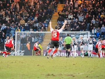 Sickener: Adam Downes celebrates as Peter Leven's free kick hits the net