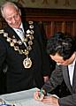 Dr Natori Yuji signs the visitors book at the town hall in front of Mayor Councillor Robin Parker.