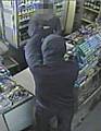 The armed robber threatens the shopkeeper at the Heywood newsagent with a knife before making off with cash.