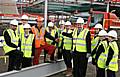 Principal Eric Jackson (fourth from right) alongside pupils and guests celebrate the topping out by helping to raise the final piece of steel.