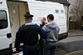 A suspect being led to a police van following early morning raids