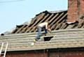 Roofer working on a house roof, without scaffolding or other safety equipment