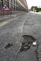 The potholes which have not been repaired. The mobile phone next to the hole is to highlight its size