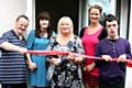 Councillor Robinson cuts the ribbon to the doors of the new centre, with service users and managers of the centre