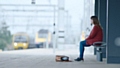 A person sitting alone and isolated on a station platform - Small Talk Saves Lives, says Samaritans