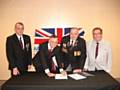 Councillor Alan McCarthy (middle left) signs the covenant with Councillor Peter Rush (right)