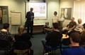 Michael Livingstone, (standing, left) and Gemma Kirk, (standing, right), deliver a presentation and to graduates at their celebration event