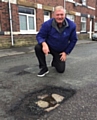 Councillor Neil Butterworth seen here with one of several potholes on Bentgate Street, Newhey