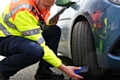 Highways England traffic officer Neil Waring checking car tyres