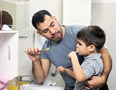 A father and son brushing their teeth at home