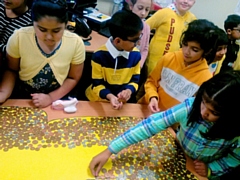 Children laying change on the giant Pudsey bear