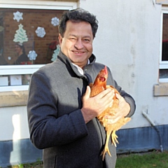 Councillor Iftikhar Ahmed, cabinet member for adult care, with one of the hens at Cleggsworth House Care Home 