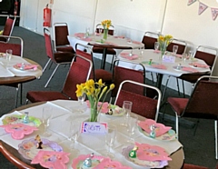 Tables set up for Mother's Day with bunting on the walls