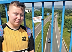 Chris Howells with one of his signs on a bridge