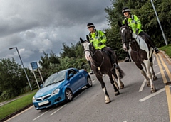 A car passing two mounted police