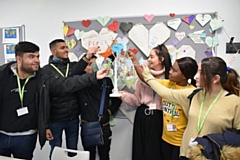 Eloise Dale (centre) and her ESOL students with their origami cranes, peace tree and peace wall