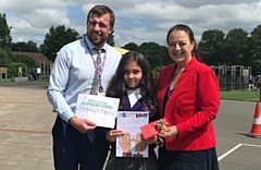 Tabassom being presented with her winning certificate, poster and voucher by staff at Sandbrook Primary 