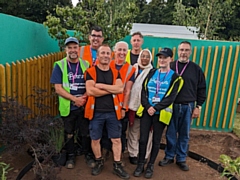 A group of Petrus volunteers and service users, halfway through the build