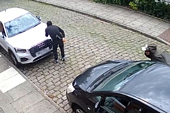 The two men creep around the side of a car, with one clearly holding a billhook machete behind his back