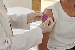 Doctor applying plaster on arm of patient after vaccination